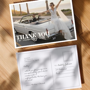 May include: A wedding thank you card featuring a photo of a bride and groom in a white convertible. The card has the text "THANK YOU for celebrating with us" and a handwritten message. The card is on a wooden surface.