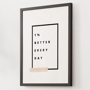 Pu&ograve; includere: Stampa incorniciata con cornice nera e sfondo bianco. La stampa presenta il testo "1% BETTER EVERY DAY" in nero, all'interno di un rettangolo nero. Un rettangolo beige si trova nella parte inferiore della stampa.