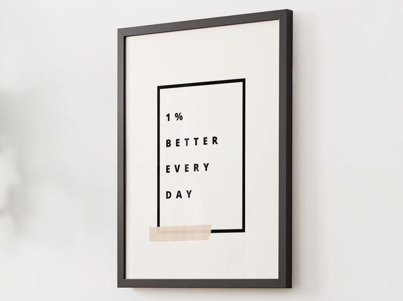 Pu&ograve; includere: Stampa incorniciata con cornice nera e sfondo bianco. La stampa presenta il testo "1% BETTER EVERY DAY" in nero, all'interno di un rettangolo nero. Un rettangolo beige si trova nella parte inferiore della stampa.