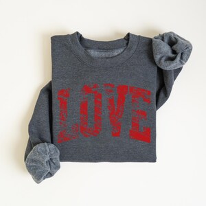 A gray sweatshirt with the word "LOVE" printed in red text on it.