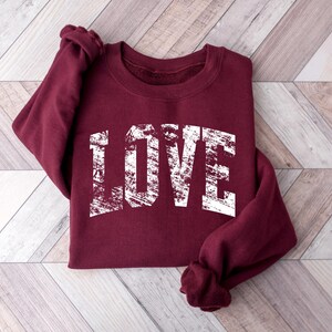 A burgundy sweatshirt with the word "LOVE" printed in white text on the front.