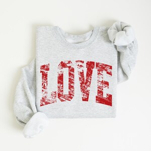 A gray sweatshirt with the word "LOVE" printed in red text on it.