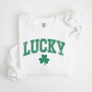 a white t - shirt with a green lucky shamrock on it
