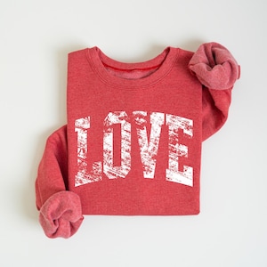 A red sweatshirt with the word "LOVE" printed in white text on it.