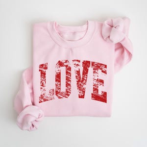 A pink sweatshirt with the word "LOVE" printed in red text on it.