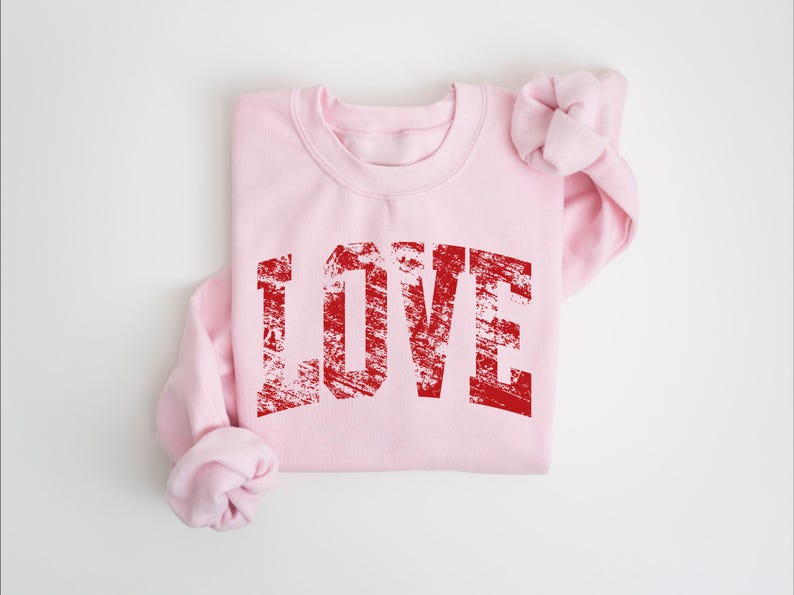 A pink sweatshirt with the word "LOVE" printed in red text on it.
