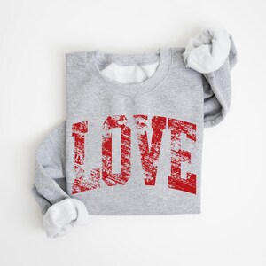 A gray sweatshirt with the word "LOVE" printed in red text on it.