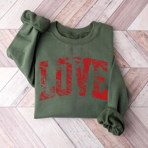 A green sweatshirt with the word "LOVE" printed in red text on it.