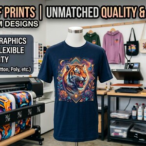 May include: A navy blue t-shirt with a vibrant tiger graphic. The image showcases a DTF printing setup, highlighting full-color graphics, soft feel, flexibility, and high durability on various fabrics. Additional apparel is visible.