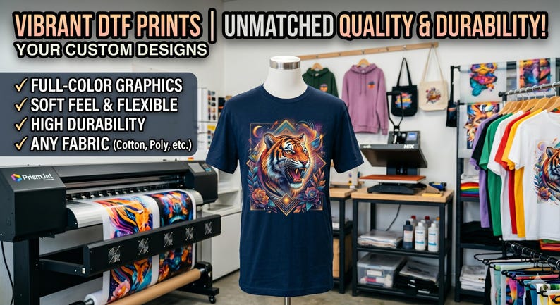 May include: A navy blue t-shirt with a vibrant tiger graphic. The image showcases a DTF printing setup, highlighting full-color graphics, soft feel, flexibility, and high durability on various fabrics. Additional apparel is visible.