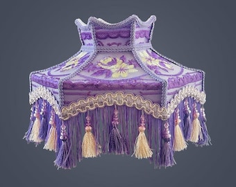 May include: A decorative lampshade in shades of purple, featuring floral embroidery and a scalloped edge. The lampshade is adorned with cream-colored tassels and beaded accents, creating a vintage aesthetic.