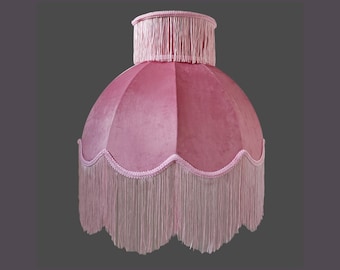 Op de afbeelding: Een roze fluwelen lampenkap met een gegolfde rand en franje.