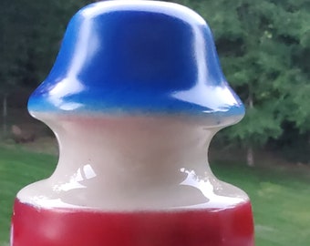 Op de afbeelding: Een decoratieve keramische flesstopper met een patriottisch kleurenschema. De bovenkant is blauw, overgaand in wit, en de basis is rood. De stopper heeft een glanzende afwerking en een unieke, afgeronde vorm.