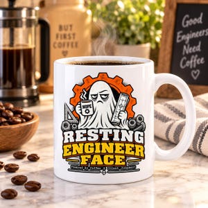 Puede incluir: Una taza de cerámica blanca con un gráfico de un fantasma sosteniendo una taza de café con la etiqueta NOPE y un plano. El texto dice RESTING ENGINEER FACE y Powered by Coffee & Silent Judgment, sobre un engranaje naranja y piezas.