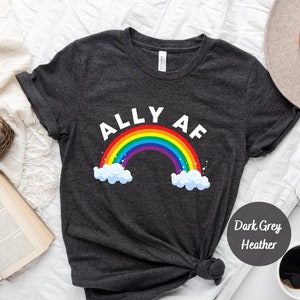 May include: Dark grey heather t-shirt with a rainbow and the text "ALLY AF".