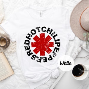 May include: White t-shirt with a black and red graphic of the Red Hot Chili Peppers logo. The logo is a red star with a black outline and the words "Red Hot Chili Peppers" written around it.