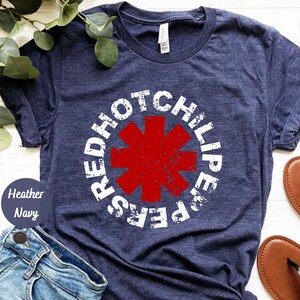 May include: A navy blue t-shirt with a white distressed circle graphic featuring the words "Red Hot Chili Peppers" and a red asterisk.