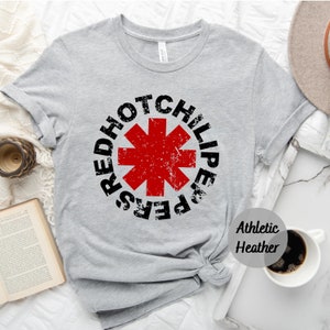 May include: Gray t-shirt with a red and black Red Hot Chili Peppers logo. The logo is a red star with a black outline and the words "Red Hot Chili Peppers" around it. The shirt is labeled "Athletic Heather".