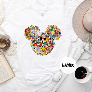 May include: White t-shirt with a colorful Mickey Mouse head design made up of various Disney characters. The text "White" is written in black on a white circle.