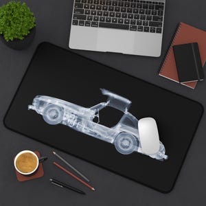 Peut inclure: Tapis de souris rectangulaire noir avec un design de voiture transparent. Une souris d'ordinateur blanche est sur le côté droit du tapis. Un ordinateur portable, des cahiers et une tasse de café sont également visibles.