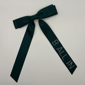 Peut inclure: Un n&oelig;ud en satin vert fonc&eacute; avec le texte "BALLIN" brod&eacute; en fil blanc.
