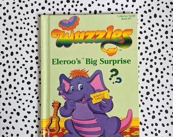 May include: A green book with the title "Wizzles" and the subtitle "Eleroo's Big Surprise?"  The book features a purple elephant with pink stripes holding a yellow ticket that says "Raffle Prize".