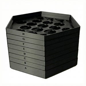 May include: A stack of eight black hexagonal trays. Each tray has circular indentations. The sides of the trays are labeled with the letters A through H. The trays are stacked on top of each other.