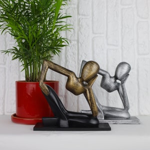 May include: Three abstract sculptures of people in a thinking pose. The sculptures are made of metal and are painted in gold, silver, and black.