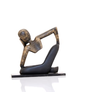 May include: A wooden sculpture of a person in a yoga pose. The sculpture is painted in shades of brown and black.