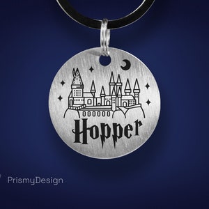 May include: A silver round tag featuring a black outline of Hogwarts castle, stars, and a crescent moon. The tag is engraved with the name "Hopper" in a black gothic font.