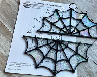 Może przedstawiać: Dwa wzory pajęczyn ze szkła witrażowego, jeden z wieszakiem, na białym arkuszu papieru z instrukcjami. Papier zawiera tekst "Spider Web Propagation Station", "Stained Glass Pattern", "Designed by Golden State Glassworks", "Copyright 2024", "@goldenstateglassworks", "You may sell any finished pieces you make from this pattern. The pattern itself is not to be sold or reproduced for sale", oraz "Size: 9.5" tall @ 100%".
