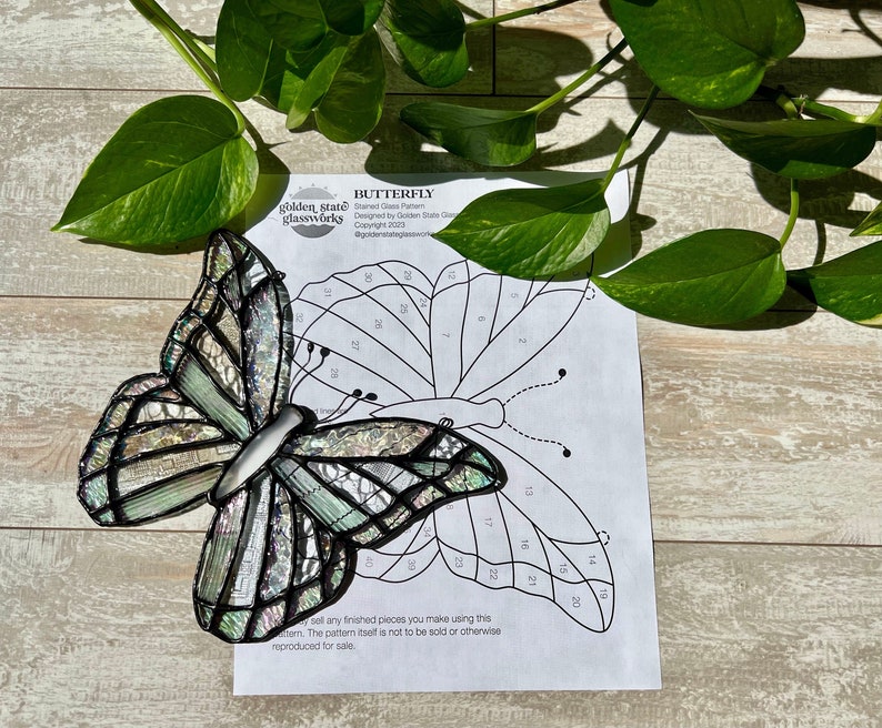 May include: A stained glass butterfly pattern with numbered sections. The pattern is printed on white paper with the title "Butterfly" and the text "golden state glassworks" at the top. The pattern is designed by Golden State Glassworks and copyrighted 2023.