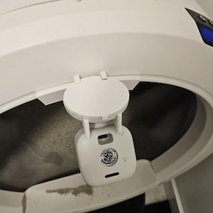 May include: A white automatic self-cleaning litter box with a white sensor attached to the top. The sensor has a black circle in the centre.