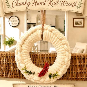 May include: A cream-coloured chunky hand knit wreath featuring a soft, textured yarn construction. The wreath is adorned with a small cluster of red berries and green leaves at the bottom and hangs from a brown ribbon. Text reads Home Sweet Home.