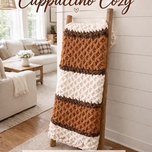 May include: A chunky hand-knitted blanket in a cappuccino colour scheme, displayed on a wooden ladder. The blanket features alternating stripes of cream, brown, and dark brown. The text "Cappuccino Cozy" is at the top, with "Chunky Hand Knit Blanket Pattern" at the bottom.