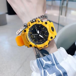 Puede incluir: Un reloj deportivo amarillo y negro con pantalla digital y agujas anal&oacute;gicas. El reloj tiene una correa amarilla y una esfera negra con n&uacute;meros blancos. La palabra "SPORT" est&aacute; impresa en la correa.