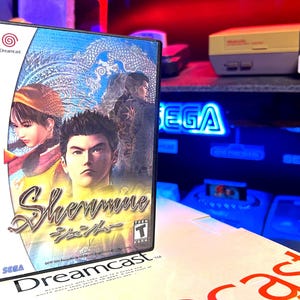 May include: A Sega Dreamcast game case with a blue, white, and red design. The game is called "Shenmue" and features a Japanese character on the cover. The case is in good condition and has a few scratches.