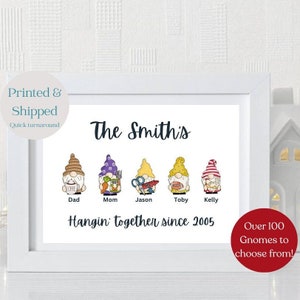 May include: A white framed print with a family of gnomes. The gnomes are wearing hats and holding items like a coffee cup, a carrot, scissors, a football, and a red and white striped hat. The text "The Smith's" is at the top of the print, and the text "Hangin' together since 2005" is below the gnomes. The text "Over 100 Gnomes to choose from!" is in the lower right corner of the print.