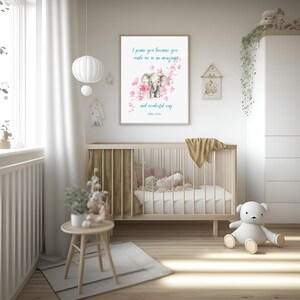 Könnte beinhalten: Ein Kinderzimmer mit einem weißen Babybett, einem weißen Teddybär, einem kleinen Holztisch und einem gerahmten Druck mit einer Aquarell-Illustration eines Elefanten und rosa Blumen. Der Druck enthält den Text "Ich lobe dich, denn du hast mich auf eine erstaunliche und wunderbare Weise gemacht. Psalm 139:14."