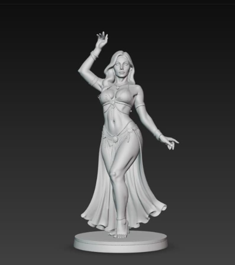 May include: A detailed, grayscale sculpture of a female figure in a belly dance costume. The figure is posed with one arm raised and the other extended, wearing a bra top, skirt, and flowing fabric. The sculpture is mounted on a circular base.