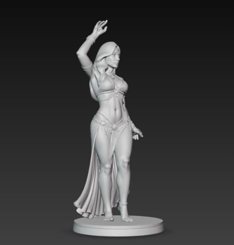 May include: A grayscale figurine of a woman in a belly dance costume, with her arm raised. The figure is standing on a circular base, with a long skirt and jewelry. The statue is a detailed representation of a dancer.