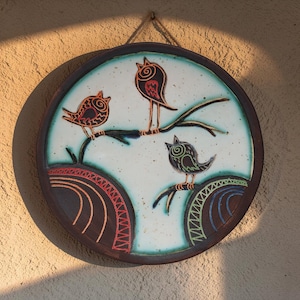 ceramic bird wall decor on textured wall with warm sunlight shadows