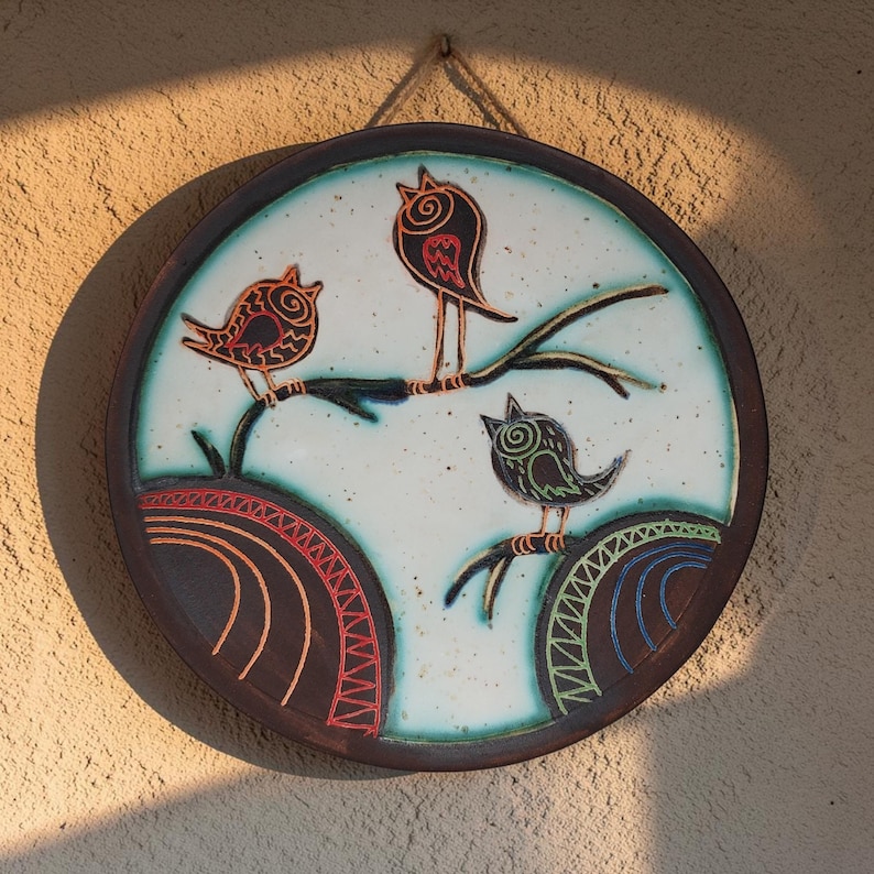 ceramic bird wall decor on textured wall with warm sunlight shadows