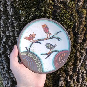 ceramic bird plate held near tree natural outdoor lifestyle pottery