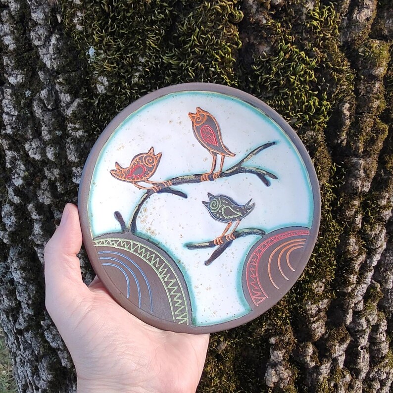 ceramic bird plate held near tree natural outdoor lifestyle pottery
