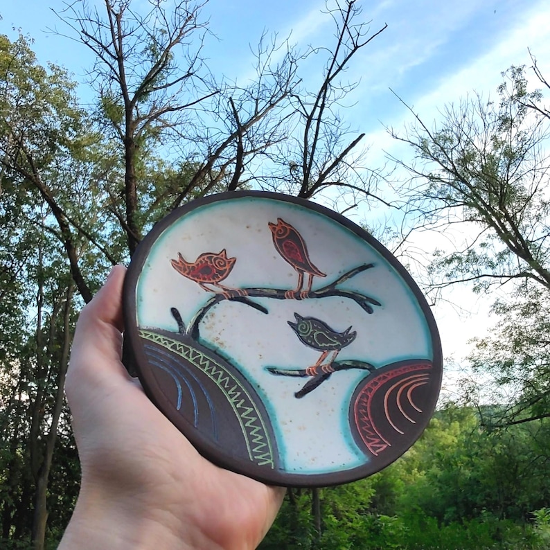 ceramic bird plate held against sky outdoor natural light