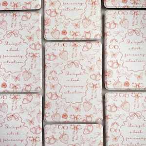 Pode incluir: Conjunto de oito  tapetes quadrados com fundo branco e um padrão floral vermelho. Os tapetes apresentam um padrão repetitivo de morangos, borboletas, pássaros, corações e laços. O texto "She's got a book for every situation" está impresso em cada tapete.