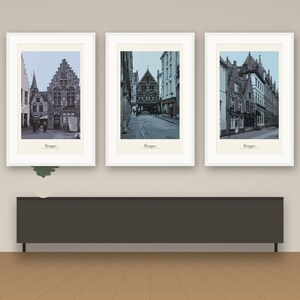 Op de afbeelding: Een set van drie ingelijste wandkunstprints met zwart-wit architectuurfotografie van Brugge, België. Elke verticale print zit in een witte lijst en toont de tekst Bruges onderaan het afbeeldingsgebied.
