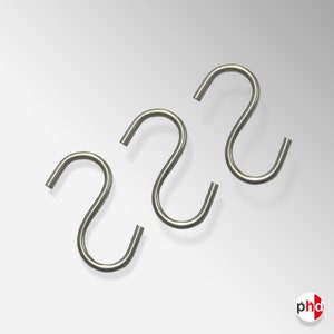 Puede incluir: Tres ganchos en forma de S plateados. Los ganchos son de metal y miden aproximadamente 5 cm de largo.