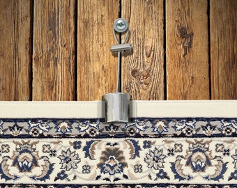 May include: A silver metal rug gripper with a cable and a screw. The gripper is attached to a wooden surface and is holding a rug in place.